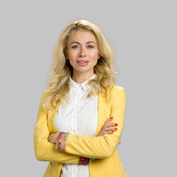 Portrait of young woman crossed arms. Portrait of smiling young business woman with crossed arms pose isolated on grey background.